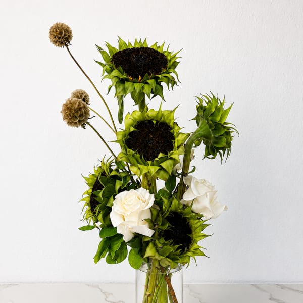 Tall arrangement of green sunflowers and white roses in a clear glass vase