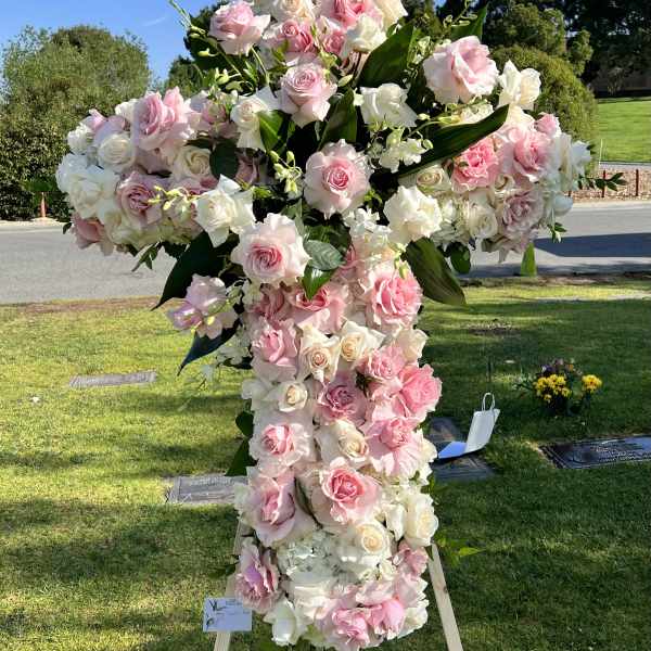 Large pink and white rose cross on a wooden stand outdoors