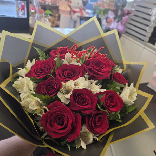 Bouquet of red roses and white flowers with a "Love You" topper