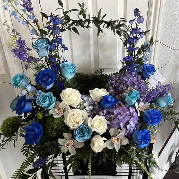 Blue, white, and purple floral arrangement with roses and orchids