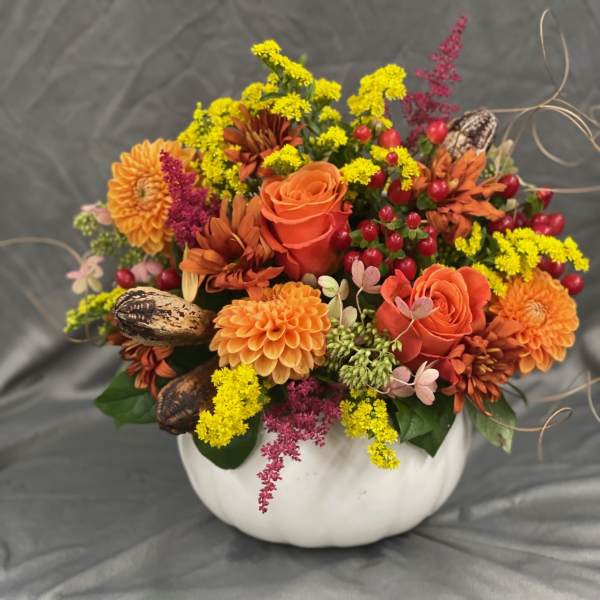 Orange and yellow floral arrangement in a white pumpkin-shaped container