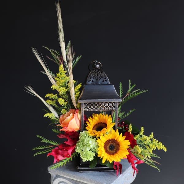 Lantern centerpiece with sunflowers, roses, and mixed foliage