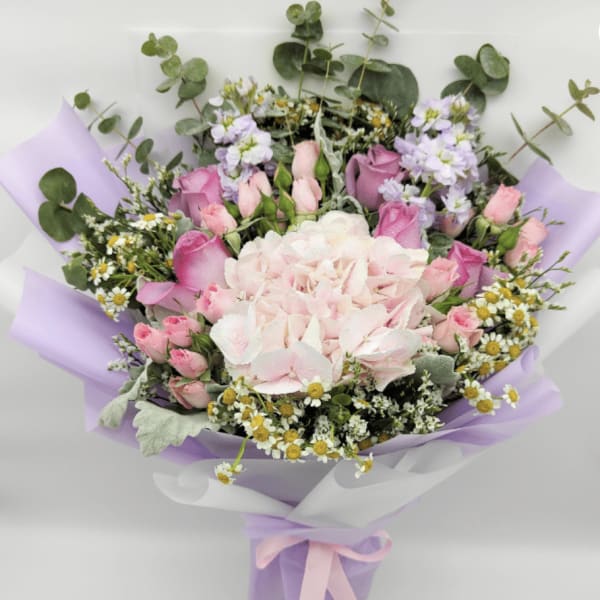 Bouquet of pink and white flowers wrapped in lavender paper