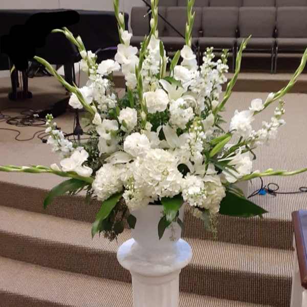 White floral arrangement in a tall pedestal vase