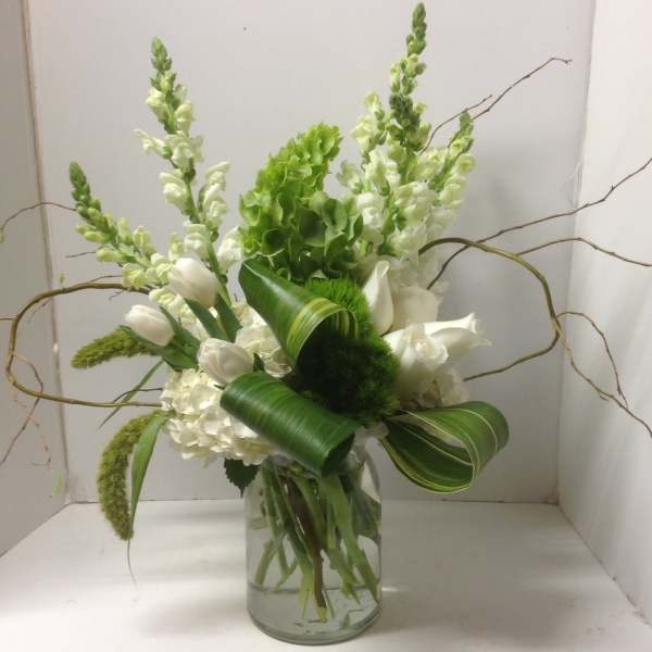 White flowers and green blooms arranged in a glass vase