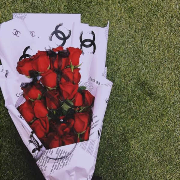 Bouquet of red roses wrapped in white paper with a black ribbon