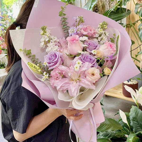 Pastel bouquet of pink and lavender flowers wrapped in lilac paper