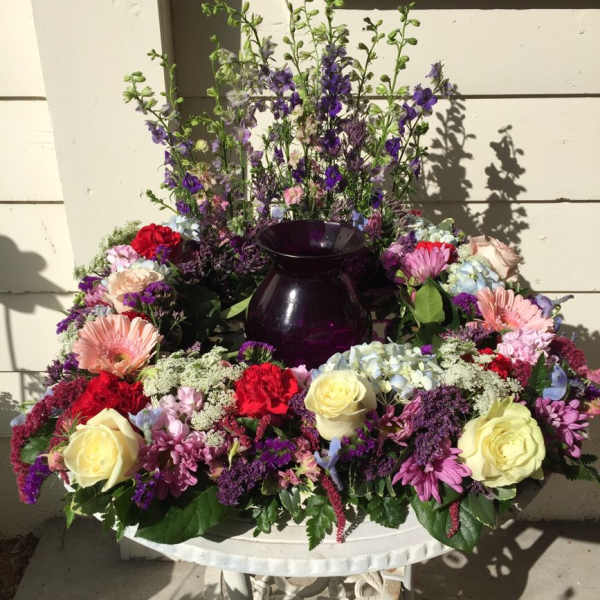 Large mixed flower arrangement with a dark purple vase
