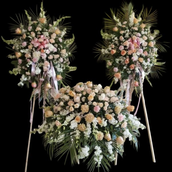 Three large floral standing sprays with pink and peach roses on easels