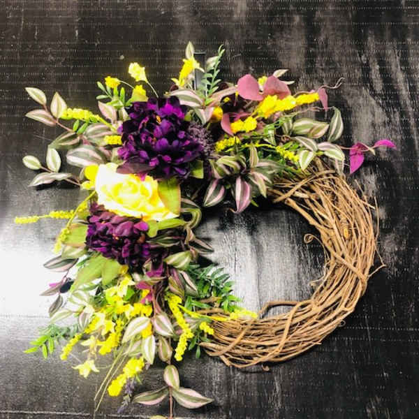 Floral wreath with purple, yellow, and white blooms on a twig base