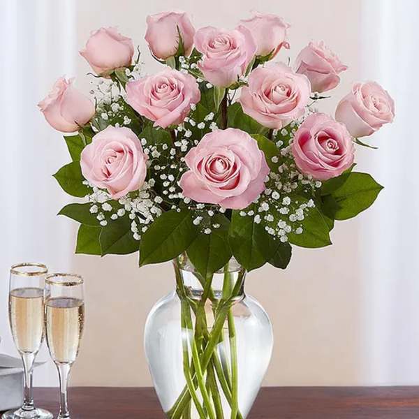 Pink roses in a clear glass vase with baby's breath