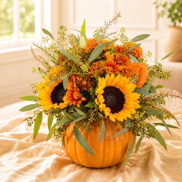Sunflower and orange chrysanthemum arrangement in a pumpkin container