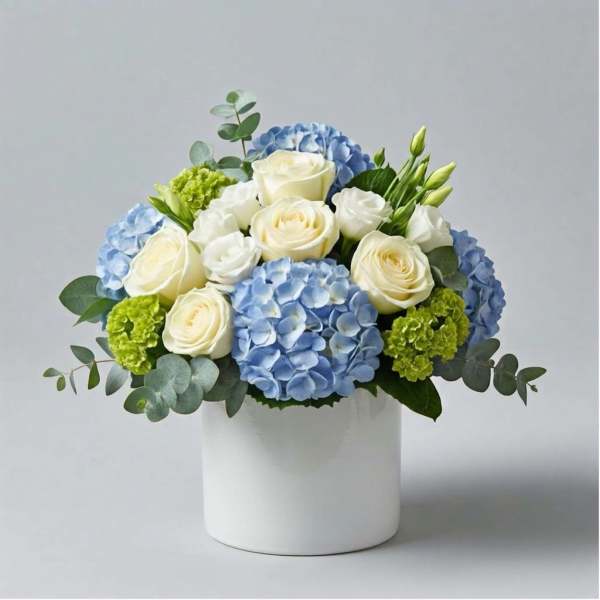 Blue hydrangeas and white roses arranged in a white vase