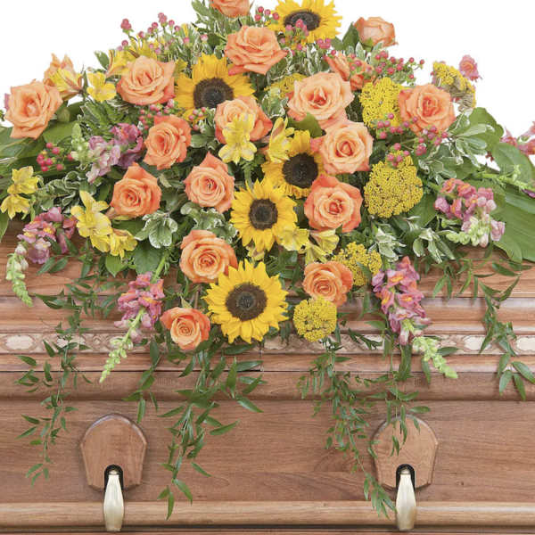 Casket spray with peach roses and yellow sunflowers