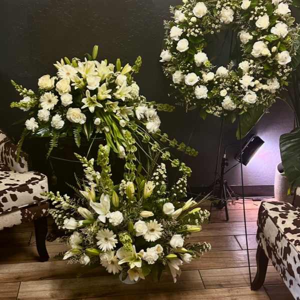 White floral wreath and two matching arrangements with lilies and roses