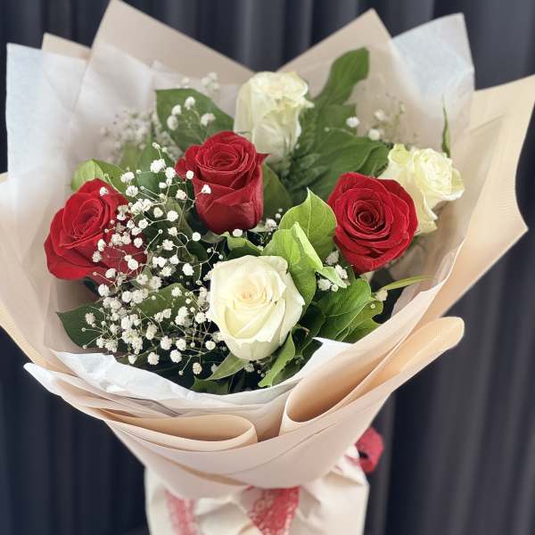 Bouquet of red and white roses with baby's breath in beige wrapping