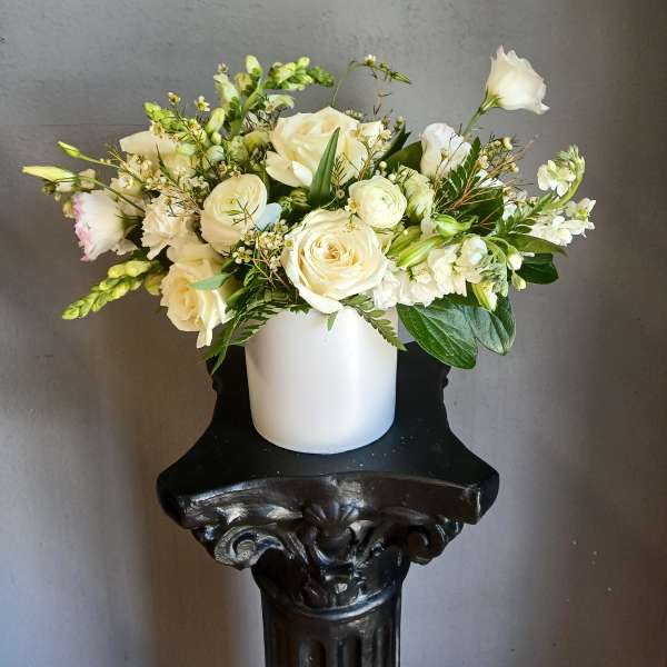 White rose bouquet in a white vase with mixed greenery
