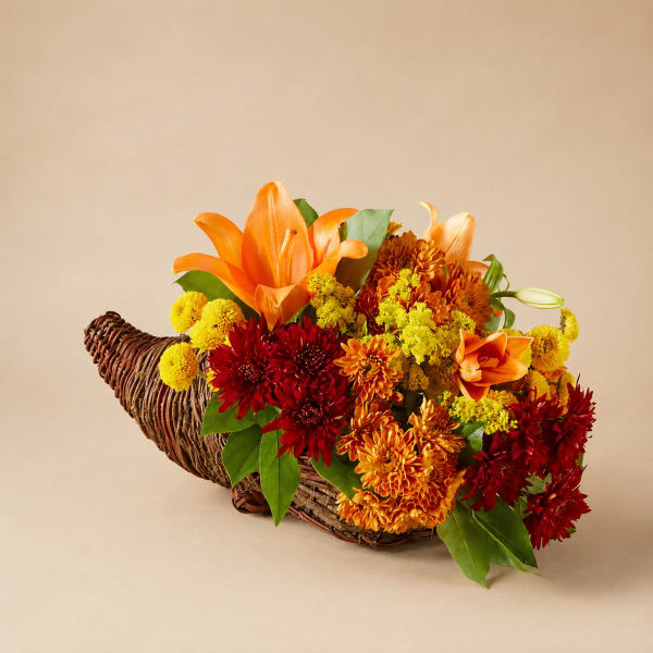 Orange and red floral arrangement in a wicker cornucopia basket