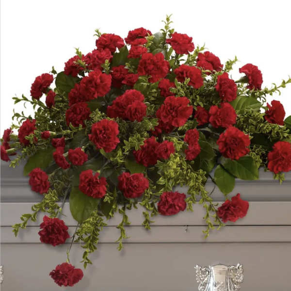 Red carnation arrangement draped over a gray casket