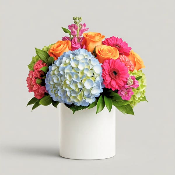 Colorful bouquet with hydrangea, roses, and gerbera daisies in a white vase