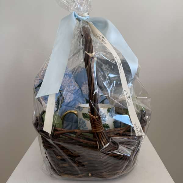 Gift basket with a blue mug and wrapped items in a wicker basket