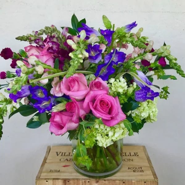 Pink roses and purple flowers arranged in a glass vase
