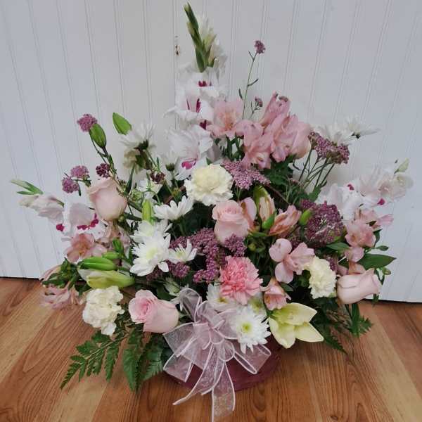 Pink and white mixed flower arrangement in a basket with a ribbon