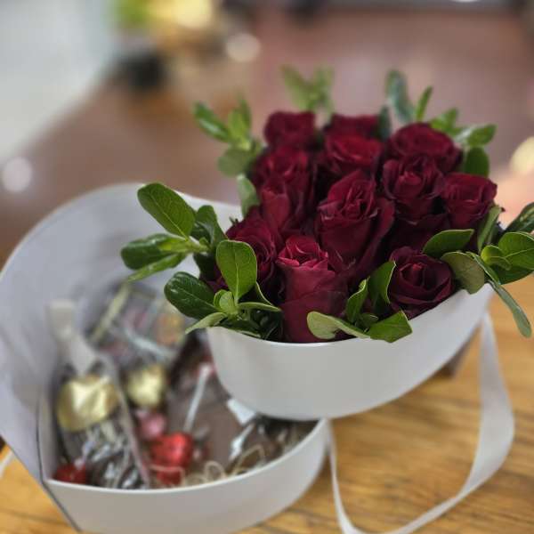 Bouquet of deep red roses with chocolates in white boxes