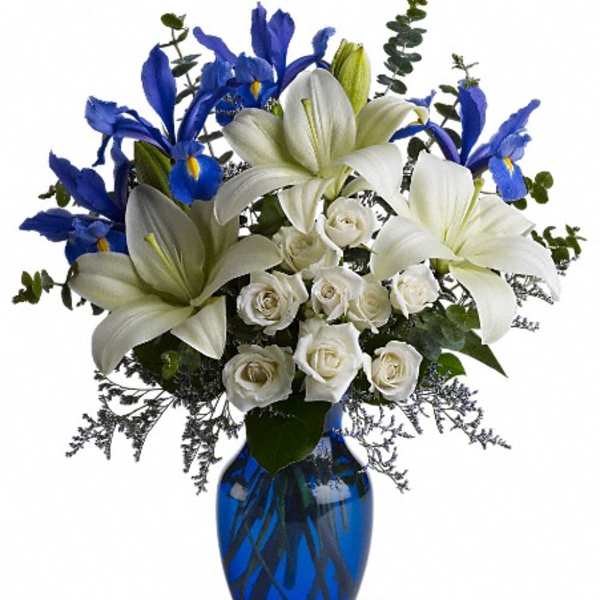 White lilies and roses with blue irises in a blue vase