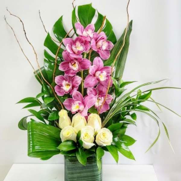 Pink orchids and white roses arranged in a tall green vase