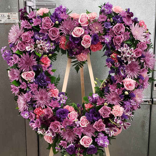 Heart-shaped floral wreath on a standing easel with pink and purple flowers