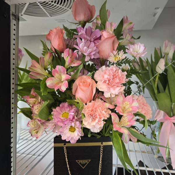 Pink mixed bouquet in a black Prada gift bag