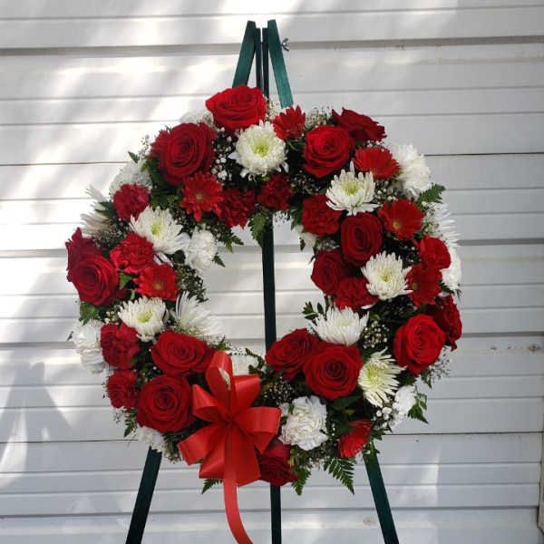 Red and white floral wreath on a standing easel with a red bow