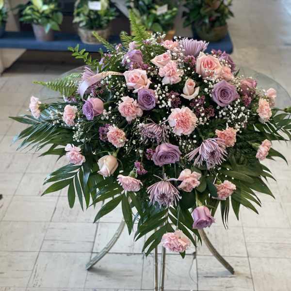 Pink and lavender floral spray on a stand with palm fronds
