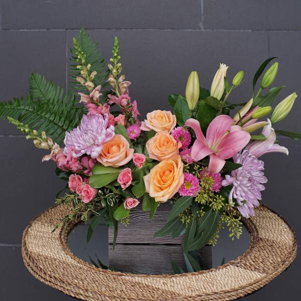 Mixed bouquet with peach roses, pink lilies, and lavender chrysanthemums in a wooden box