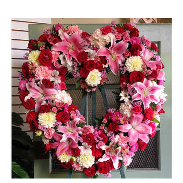 Heart-shaped floral wreath with pink lilies, red roses, and carnations