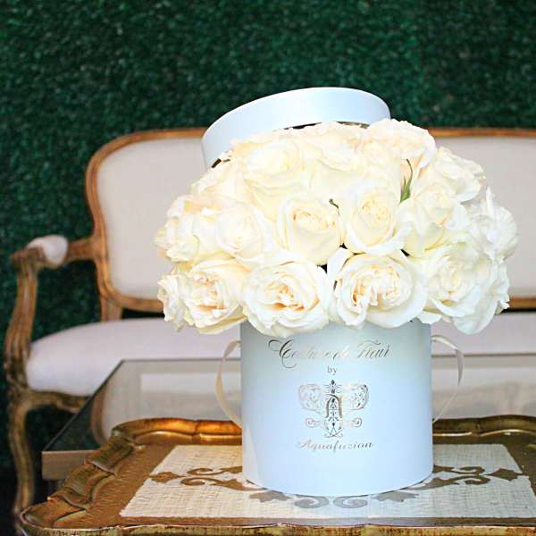 White roses arranged in a round hatbox on a table
