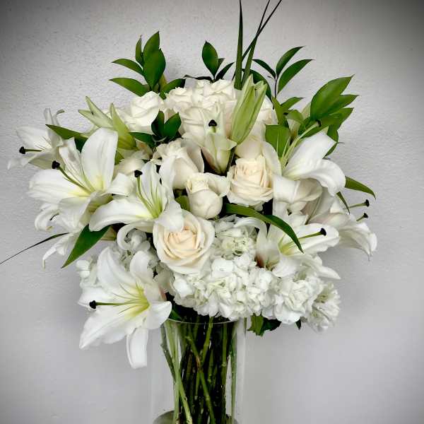 White lilies and roses arranged in a clear glass vase
