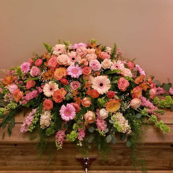 Large pink and peach floral casket spray with roses and daisies
