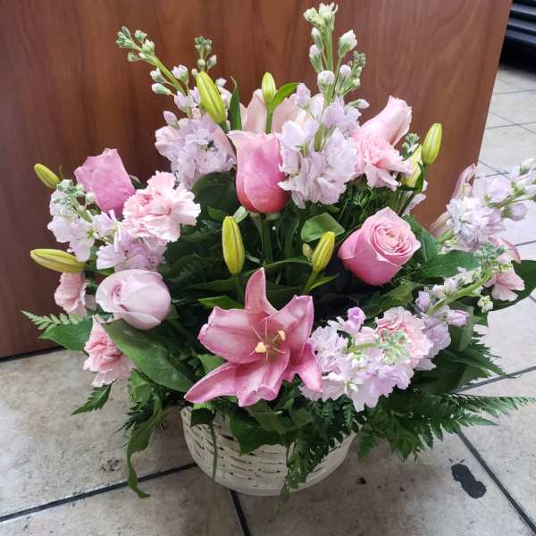 Pink lilies and roses arranged in a white basket