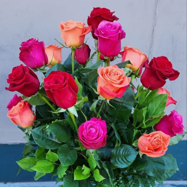 Bouquet of red, pink, and peach roses in a glass vase