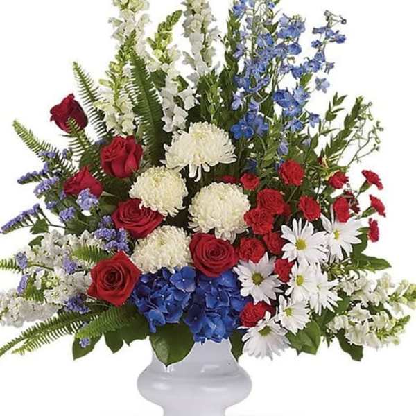 Mixed red, white, and blue floral arrangement in a white vase