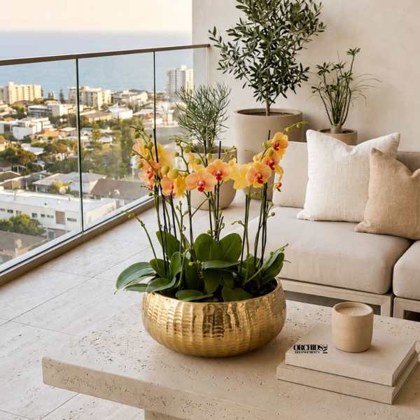 Potted yellow-orange orchids in a gold bowl on a patio table