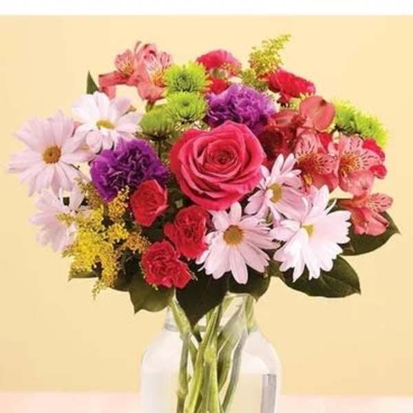 Mixed bouquet of pink roses, daisies, and carnations in a glass vase