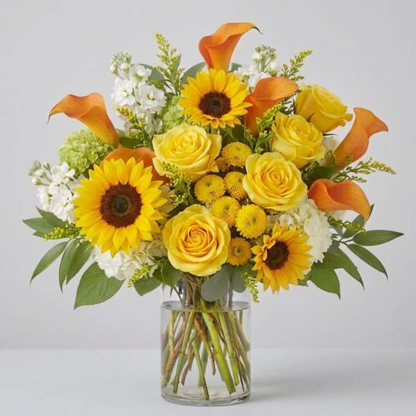 Yellow roses, sunflowers, and orange calla lilies in a glass vase