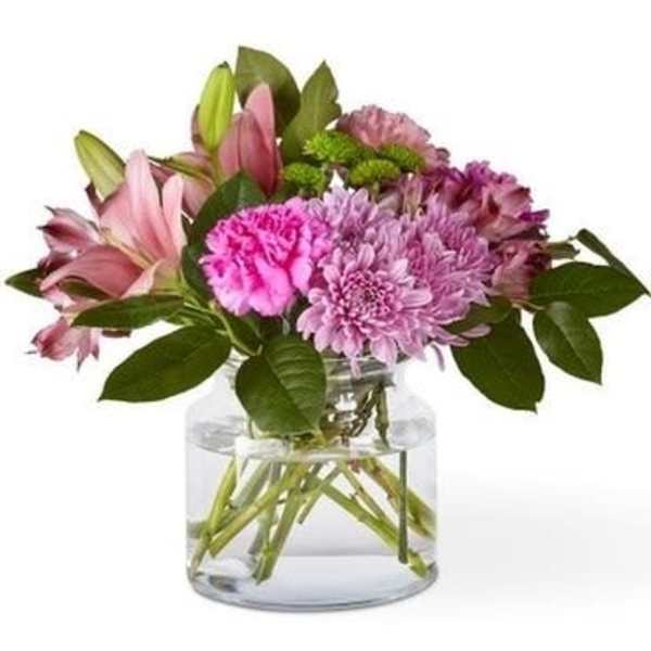 Pink lilies and purple flowers in a clear glass vase