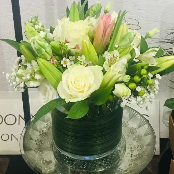 White and pale green floral arrangement in a glass vase
