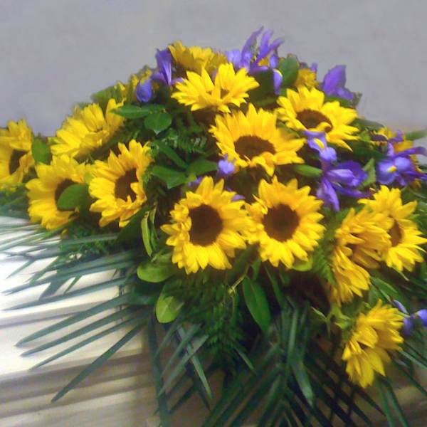 Yellow sunflowers and purple flowers arranged in a low spray
