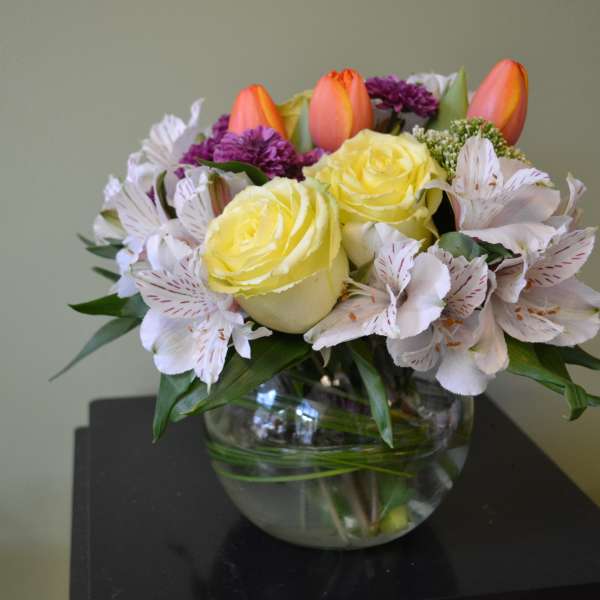 Yellow roses and white alstroemeria in a glass bowl vase