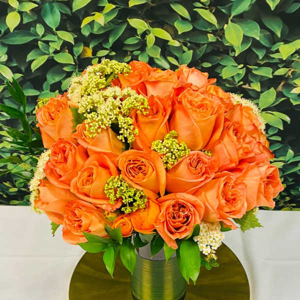 Orange roses arranged in a gold vase on a round gold base